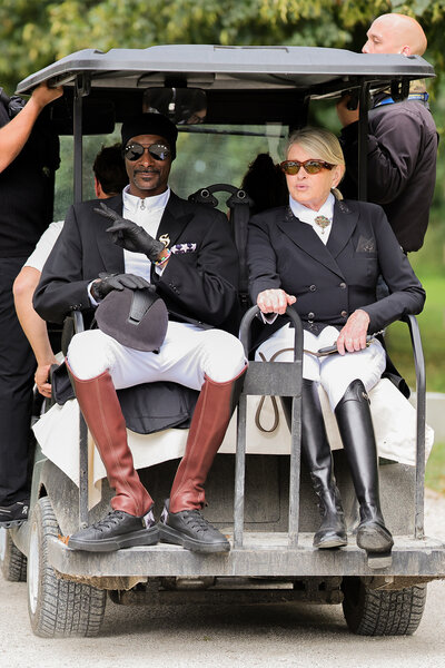 Snoop Dogg and Martha Stewart in the back of a golf cart wearing equestrian gear