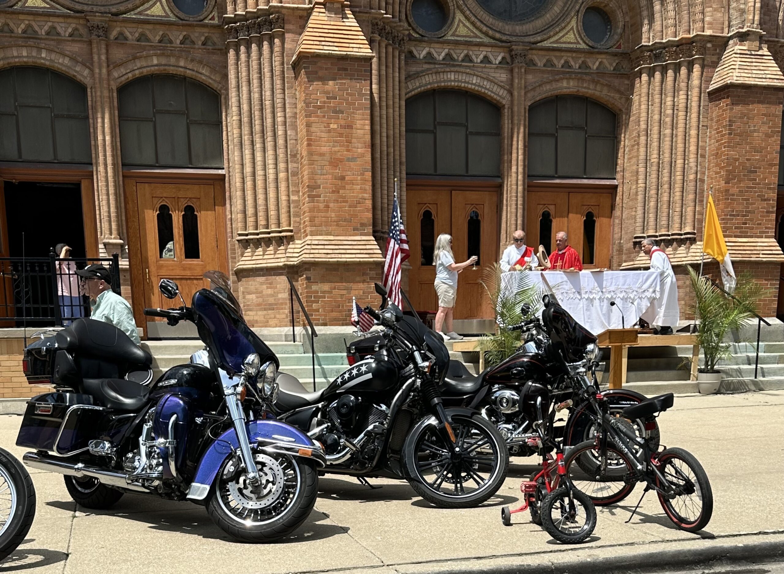 a few of the motorcycles that were parked in front of the church along with a couple bicycles