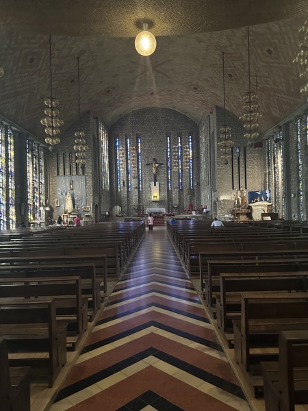 The interior of Sanctuaire de Notre Dame de Fatima. The church was built in the years after World War II. The striking thing here is the tile work on the center aisle which is a repeating pattern of chevrons leading to the sanctuary at the front of the church.