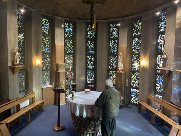 The baptismal chapel of Sanctuaire de Notre Dame de Fatima, a small round room with pews surrounding the altar which is formed by a covered baptismal font in the center of the room
