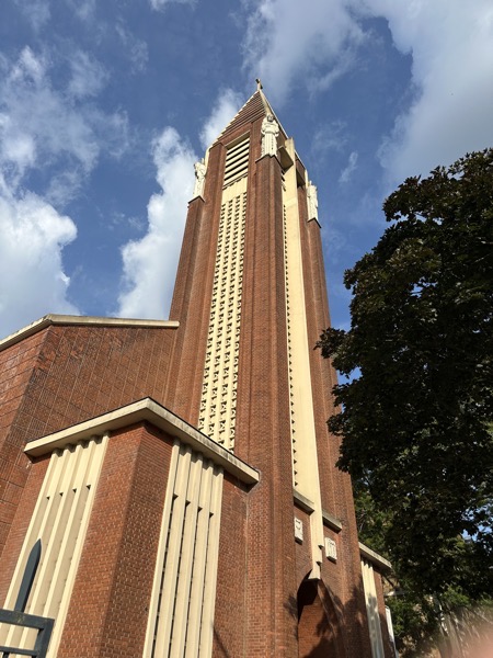 The front of the church looking up at the bell tower. The churhc was built in the 1930s when the Paris defensive wall was removed opening new terrain on the edge of Paris for development. The style of the church is kind of art deco with four statues of saints on the corners of the bell tower near its summit