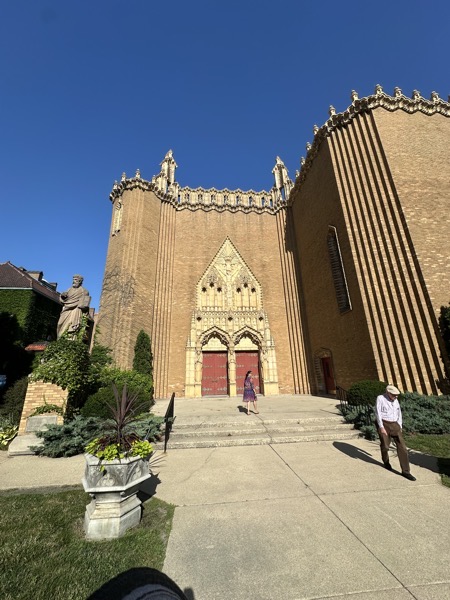 The frontish entrance to Saint Thomas the Apostle,, Rather than presenting a grand façade that leads directly into the nave, instead, with doors on the sides of the narthex. The church itself is a gothic-style building clad in brick