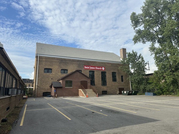The Saint James parish hall, a large brick building with a parking lot in front