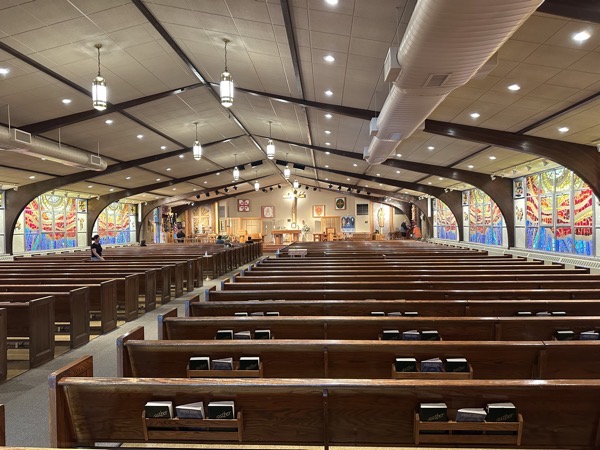 The interior of St Patricia church in Hickory Hills. The vaulted ceiling is marked by dark wood arches which have the effect of making the ceiling feel lower trhan it is, The overall style is typical of 1960s churches