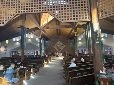 The view from the back of the church of the sanctuary. It’s the modern semicircle design for the church with pews arranged to keep everyone as close as possible to the sanctuary. Today was a school Mass day so the contingent of retirees in attendence were banished to the back of the church, one of whom is giving me a disapproving look as I photograph the church.