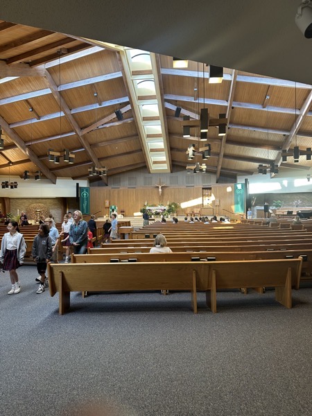 The interior of the church. There is a vaulted ceiling with a line of skylights at the peak of the roof. The church is laid out in the newer semi-circle arrangement meant to bring the congregation closer to the sanctuary.