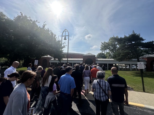A view of the church building from the outside with parishioners processing inside.