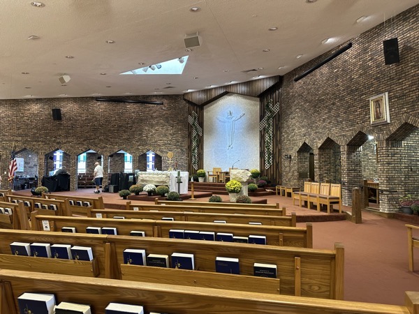 The interior of the church. Some of the distinct features include arched openings in the brick walls on either side of the sanctuary a relief sculpture of the risen Christ on the back wall of the sanctuary where a crucifix normally is placed.