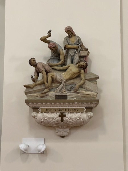 A small sculpture of Jesus being nailed to the cross that’s part of the stations of the cross at this church