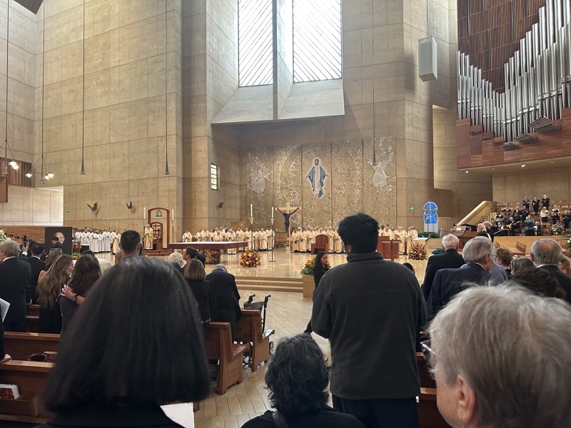 IMG_0959.jpeg The sanctuary at the Cathedral of Our Lady of the Angels. The priests are arrayed at the back of the sanctuary in gold chasubles. The purple and red caps (zukketahs) are worn by the bishops. The tall man with the red zukketah is Roger Mahoney, the archbishop (cardinal) emeritus of Los Angeles. Archbishop Gonzalez is standing before the cathedra (elaborate chair designated for the bishop/archbishop at his cathedral).