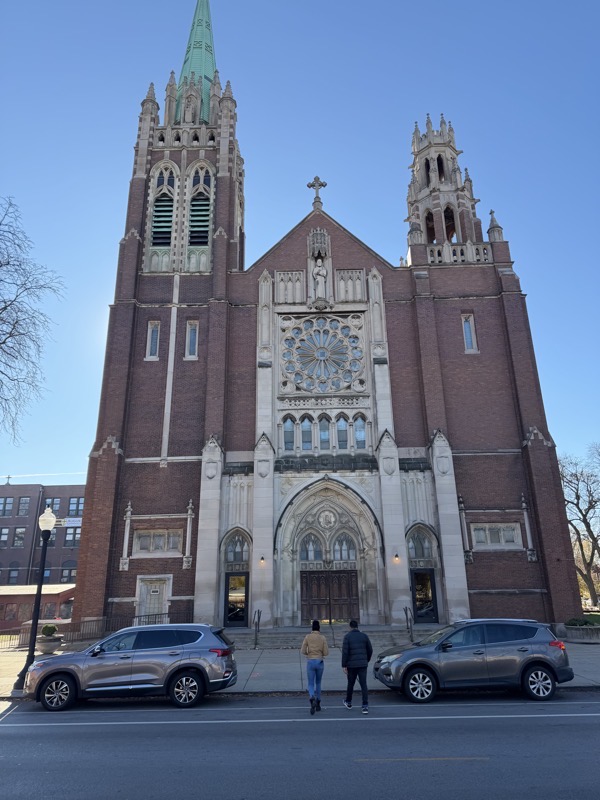 The front façade of St Columbanus/St Moses the Black, a brick and granite church in a neo-gothic style with two bell towers blanking the entrance.