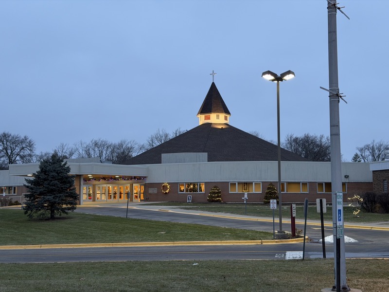 IMG_1180.jpeg The exterior of the church, a low-slung building with a pyramidal roof topped with a bell tower